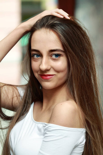 Portrait young sexy brown long haired girl in white top stay.Smiling.Blue eyes - 写真・画像