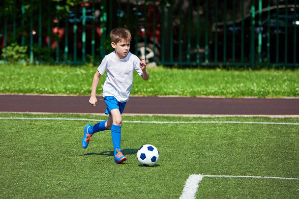 Boy football player running with ball on green lawn - Фото, зображення