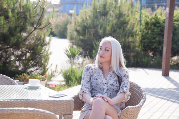 blondi tyttö istuu rannalla ravintola kahvia
 - Valokuva, kuva