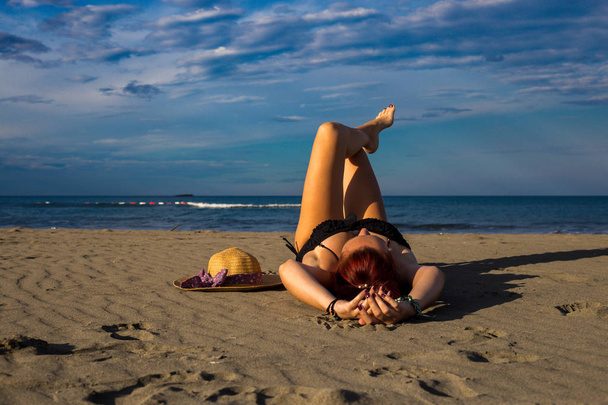 Young tanned good looking redhead laying on a sandy beach with a - Photo, Image