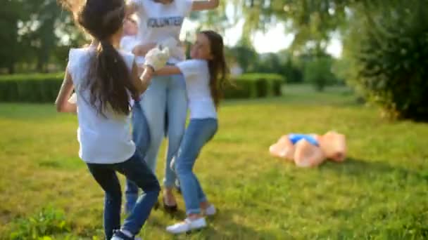 Excited children sending volunteer sprawling in park - Кадры, видео