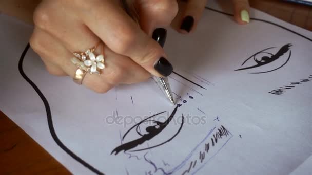 young girl draws eyebrows on a paper face - Materiał filmowy, wideo