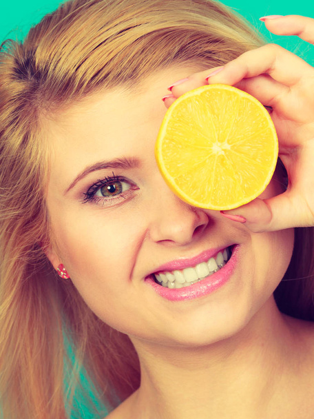 Girl covering her eye with lemon citrus fruit - 写真・画像