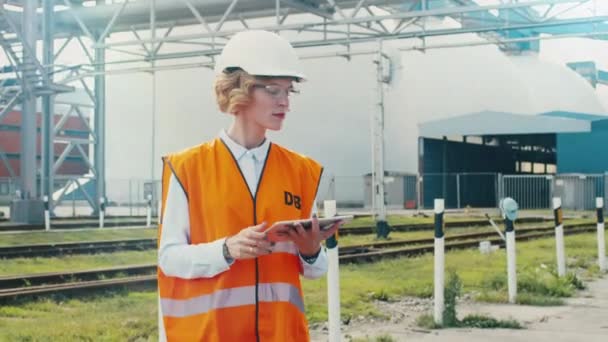 Woman in Hard Hat and Safety Vest is Using Tablet PC on Railway Station  - Felvétel, videó