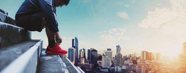 Gyönyörű ázsiai srác árukapcsolás futócipő, felkészülés futó, városi hátterű, Napkelte - Fotó, kép