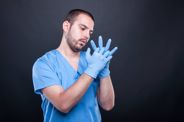Arts met scrubs vaststelling zijn latex handschoenen - Foto, afbeelding