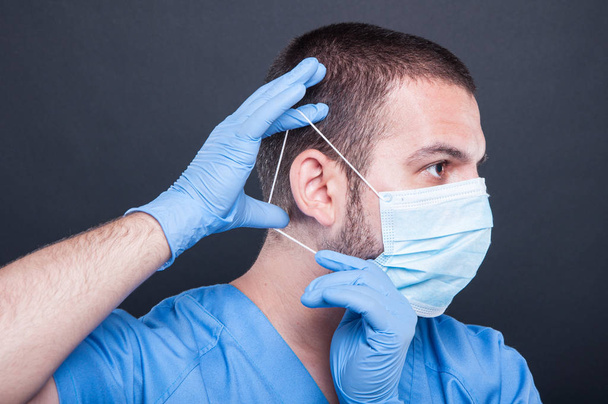 Sivukuva lääkäri laittaa hänen steriili naamio
 - Valokuva, kuva