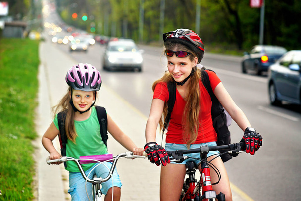 Kız çocuk sarı Bisiklet şeritli üzerinde Bisiklete binme. Yolda araba var. - Fotoğraf, Görsel