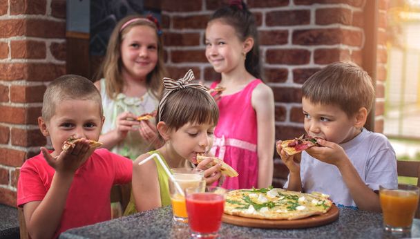 Happy children eating pizza and having fun together - Fotoğraf, Görsel