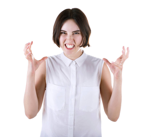 A depressive young woman with a dark haircut and in casual white blouse, isolated on a white background. The angry and frustrated office lady. - Foto, Imagen