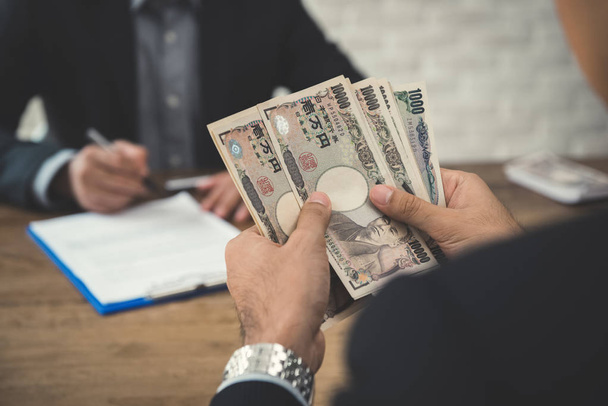 Homme d'affaires comptant de l'argent, billets de banque en yen japonais, tout en faisant
 - Photo, image
