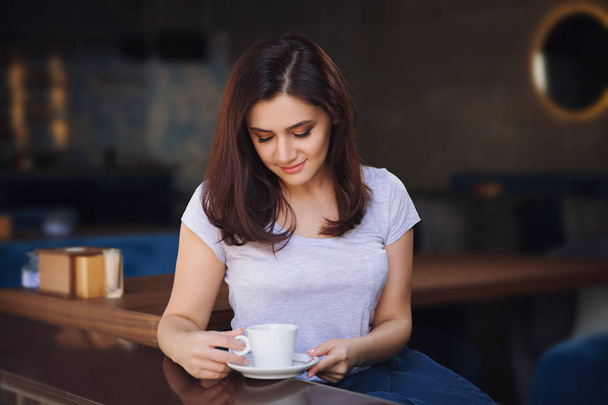 Lächelnde, gut gelaunte Frau sitzt mit einer Tasse Kaffee im Café. - Foto, Bild