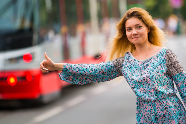 Νεαρή γυναίκα να κάνει το ωτοστόπ σε έναν δρόμο της πόλης - Φωτογραφία, εικόνα