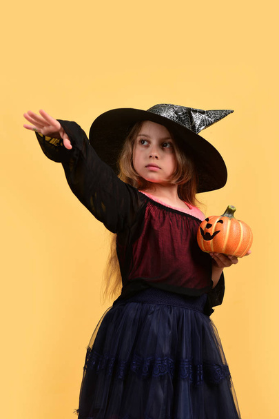 Girl with carved orange pumpkin isolated on warm yellow background - Foto, Imagem