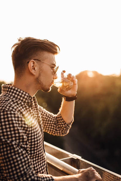 Stylish man sit on the table and drink whiskey - Photo, image