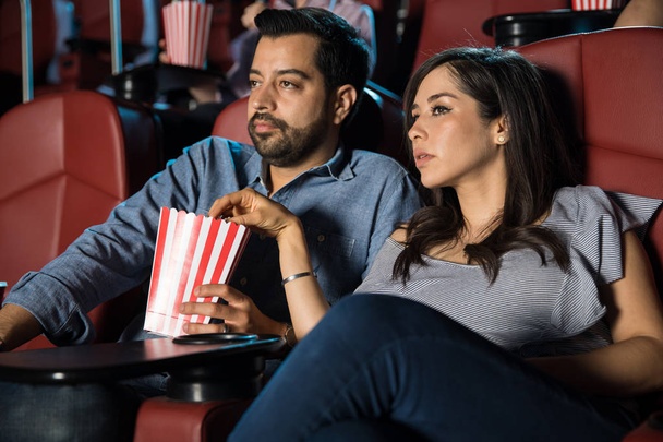 Couple eating popcorn at cinema - Valokuva, kuva