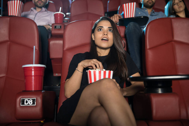 Женщина смотрит кино и ест попкорн
 - Фото, изображение