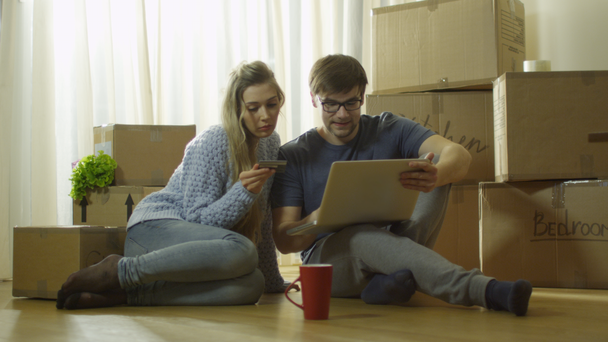 Fiatal pár használ Laptop részére Online Bevásárlás-új házban. - Felvétel, videó
