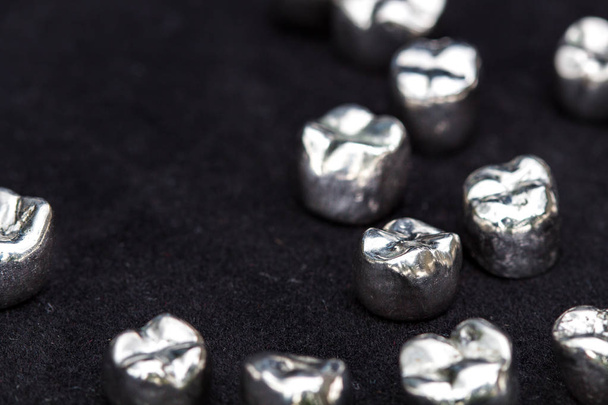 Corone dentali in metallo argentato su superficie nera scura
. - Foto, immagini