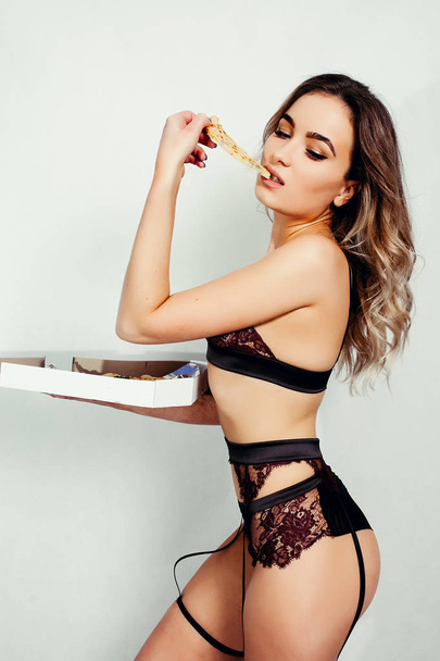 young sexy woman in black underweartasty slice of pizza - Valokuva, kuva