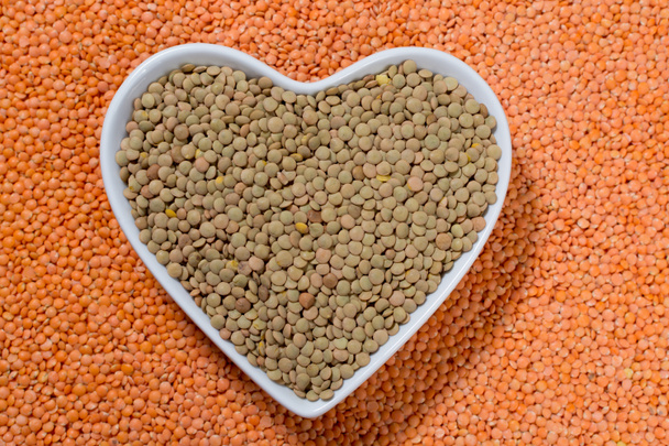 Coração forma tigela com lentilhas verdes sobre fundo lentilhas vermelhas - conceito de comida saudável
 - Foto, Imagem