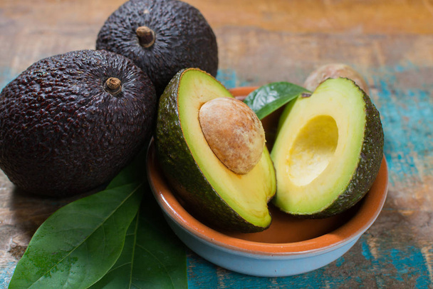 Ripe fresh avocado with leaves on blue wooden table - healthy food concept - Photo, Image