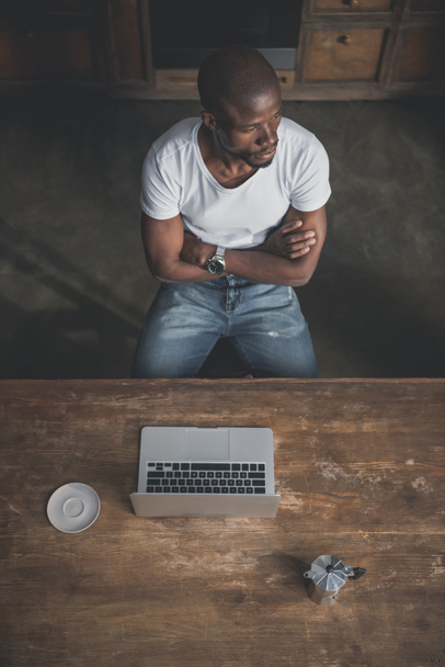 Uomo afroamericano con computer portatile a tavola
 - Foto, immagini