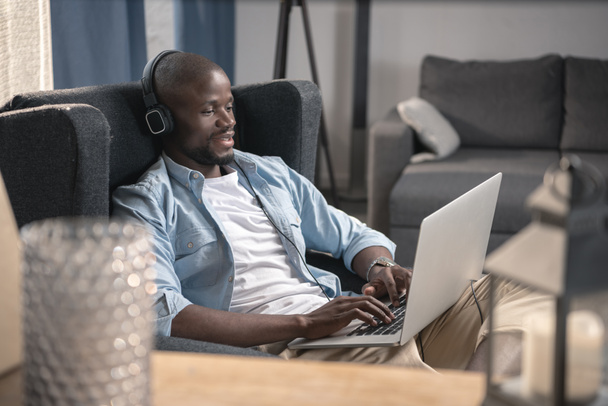 Uomo afroamericano che utilizza il computer portatile a casa
 - Foto, immagini