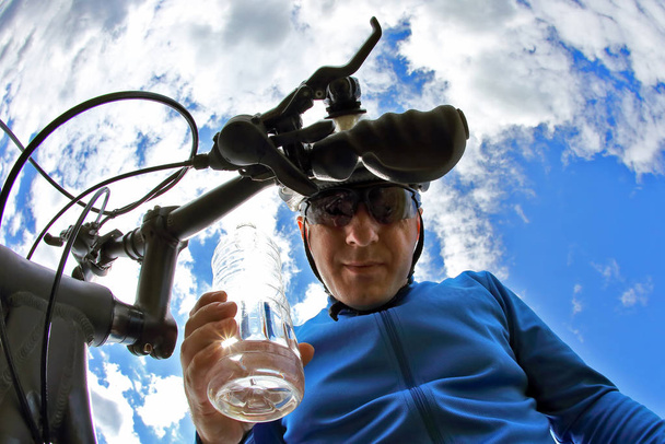 cyclist with a bike with a bottle of water on sky background - Foto, immagini