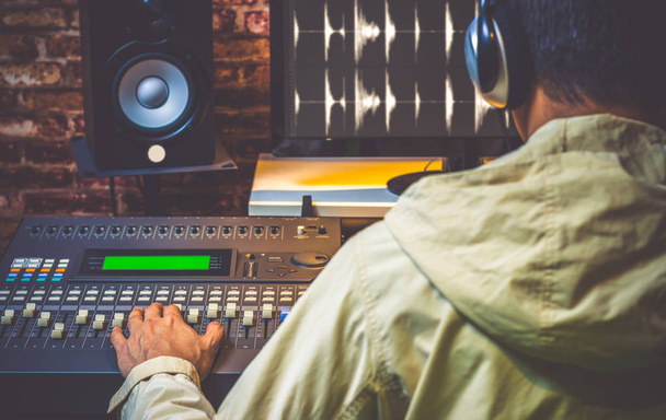 back of asian sound engineer working in digital sound editing studio, DJ working in broadcasting studio, focus on hands - Φωτογραφία, εικόνα