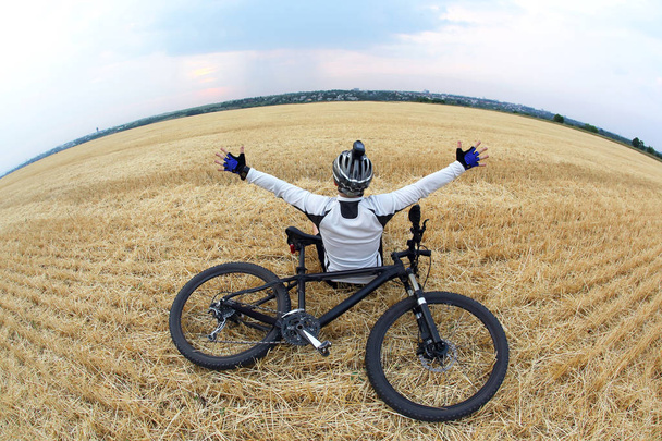 rider with raised arms sitting on a harvested field - Photo, Image