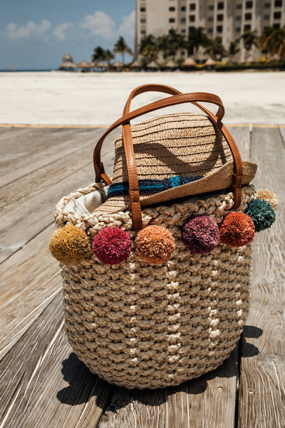 Stylish straw bag and hat on the wooden bridge at the tropical b - Valokuva, kuva