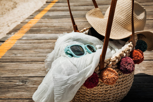 Straw bag and summer accessories on the wooden bridge at the bea - Photo, Image