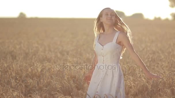Podekscytowana kobieta przędzenia w polu pszenicy o zachodzie słońca - Materiał filmowy, wideo