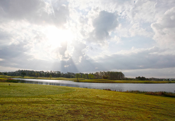 felhős nap és a háttérégbolt golfpálya - Fotó, kép