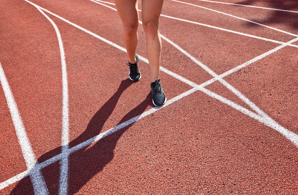 Close up on beautiful female legs with pink shoes on the running track - Foto, afbeelding