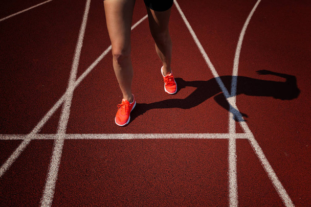 Close up on beautiful female legs with pink shoes on the running track - Foto, afbeelding