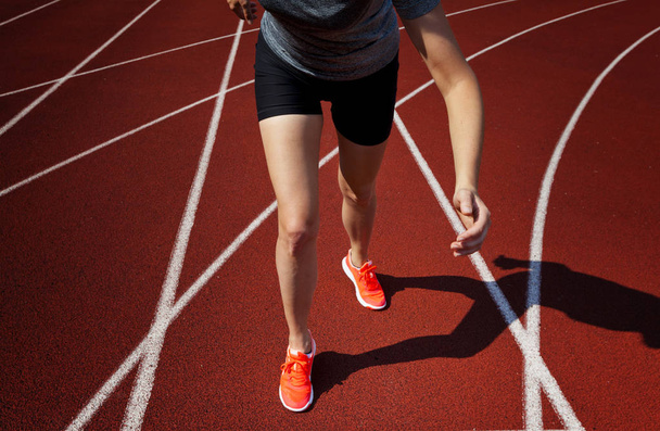 Red running track  with female runner, close up on legs - Fotoğraf, Görsel