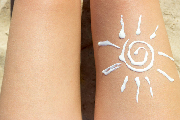 Femme bronzant sur la plage avec un dessin de soleil sur sa jambe avec de la crème
 - Photo, image
