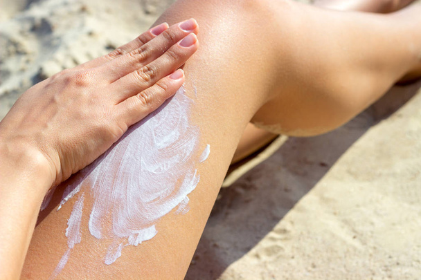 女性の手が足に日焼け止めクリームを適用することでクローズ アップ。スキンケア。太陽の保護クリーム、彼女の滑らかな日焼けした脚に. - 写真・画像