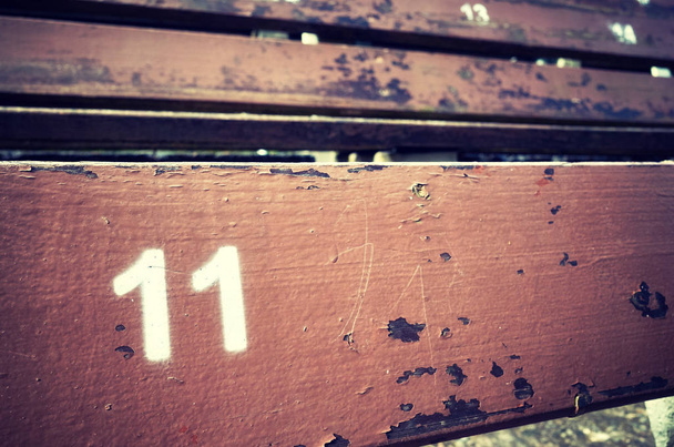 Номер одиннадцать, нарисованный на старом деревянном сидении
. - Фото, изображение