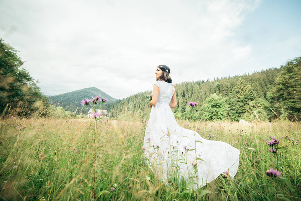 Beautiful young woman wearing elegant white dress standing on a feild - Фото, зображення