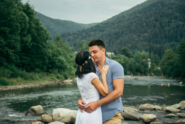 couple stands near mountain river with mountains on background - Photo, Image