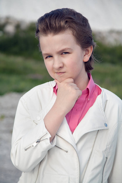 прохладная белая одежда модный мальчик с грубым брутальным лицом на улице возле большой горы
 - Фото, изображение