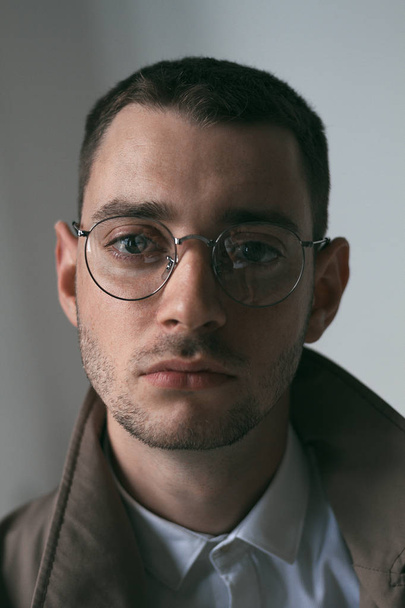 Ένα μοναχικό όμορφος άντρας με γυαλιά με διαφορετικές διαθέσεις και ένα αδιάβροχο - Φωτογραφία, εικόνα