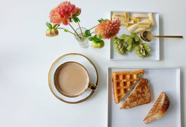Vafle, Frech toast, ovoce a latte s květinami a zlatem lžíce na bílé stolní nádobí - Fotografie, Obrázek