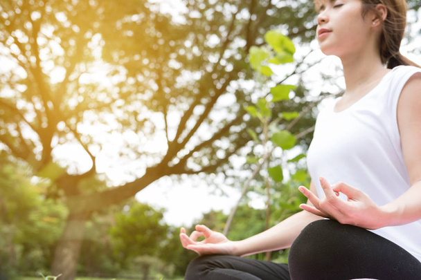 Yoga al aire libre en parque público. Mujer asiática se sienta en posición de loto
 - Foto, Imagen