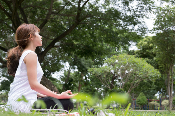 Yoga im Freien im öffentlichen Park. Asiatin sitzt in Lotusstellung - Foto, Bild
