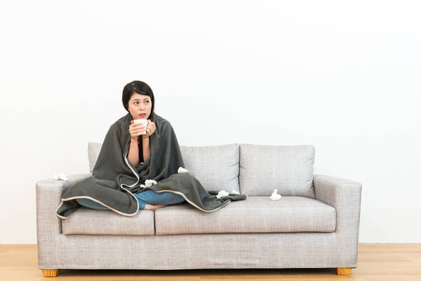 lady sitting on sofa couch and holding hot water - Foto, afbeelding
