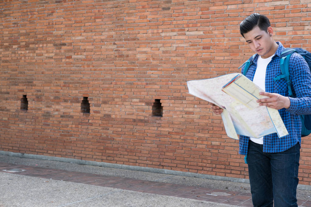 Junge Reisende lesen Landkarte. asiatischer Mann trägt blaues Hemd und Jea - Foto, Bild